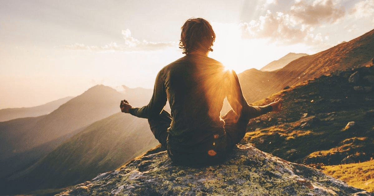 Person meditating on mountain at sunrise — aligning with natural energy and the Tao